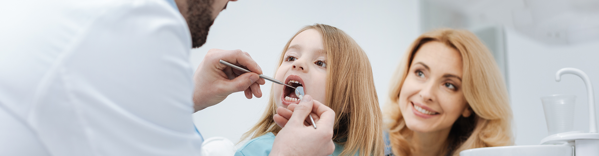 dentist using dental tools in child's mouth